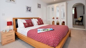 Ein Schlafzimmer mit Bett, Nachttisch, Lampe und einem Schrank mit Spiegeln.