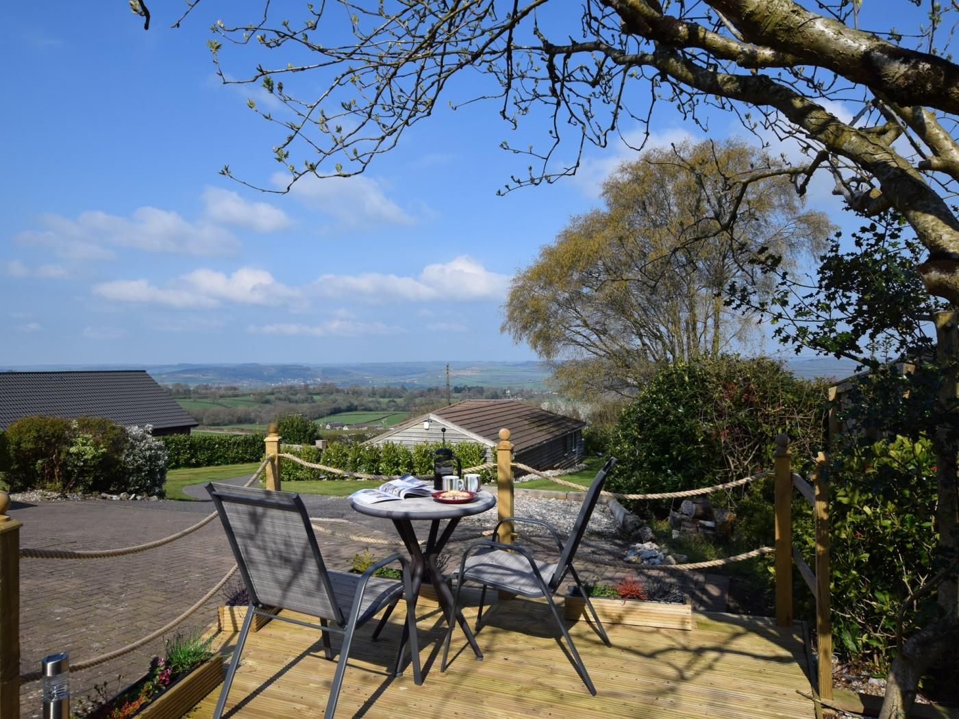A wooden deck with a table and chairs overlooking a rural landscape.
