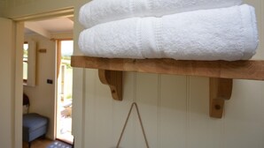 A stack of white towels on a wooden shelf in a room with a door leading to an outdoor area. - 1 Bed in Usk- (oc-63292) (Llangwm)