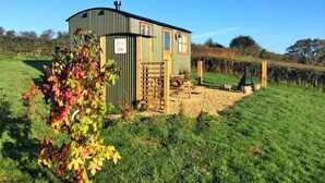 A small, single-story structure with a sloped roof, a wooden bench, and a gravel area in front. - 1 Bed in Usk- (oc-63292) (Llangwm)