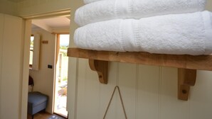 Ein Stapel weißer Handtücher auf einem Holzboden in einem Raum mit einer Tür, die nach draußen führt.