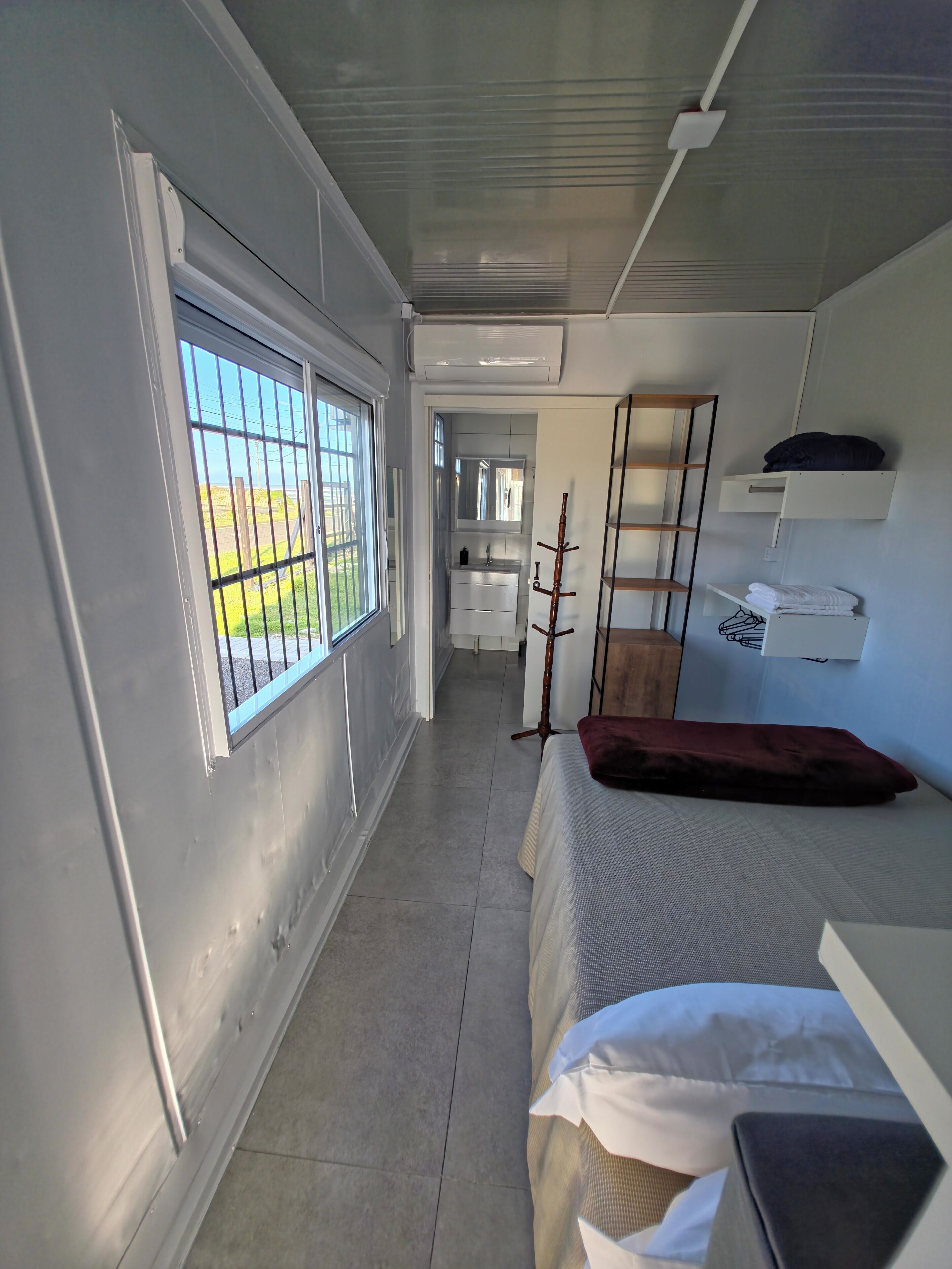 Un dormitorio con cama, ventana con rejas, armario y espejo.