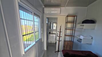 Un dormitorio con cama, ventana con rejas, armario y espejo.