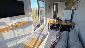 Interior moderno de uma RV com sofá, mesa de jantar e televisão fixada na parede.