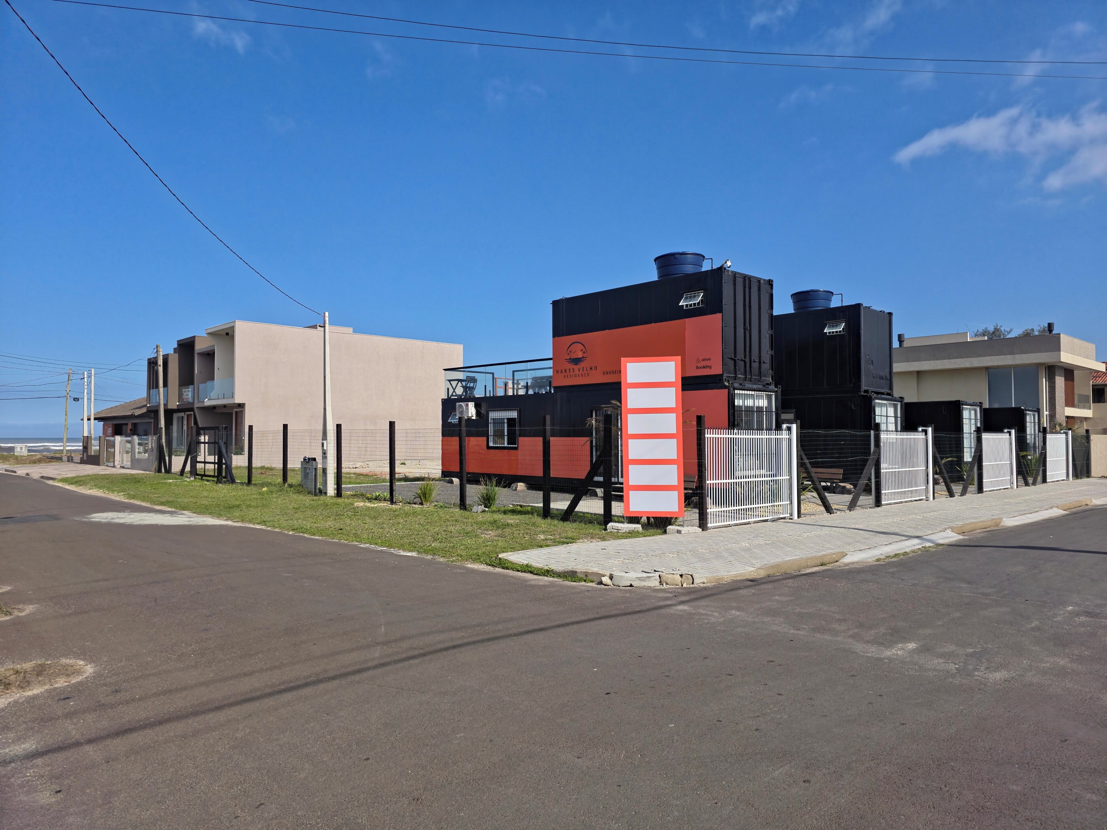 Un edificio moderno con techo plano, un depósito de agua grande y un área cercada.