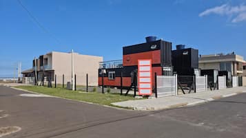A modern building with a flat roof, a large water tank, and a fenced area.