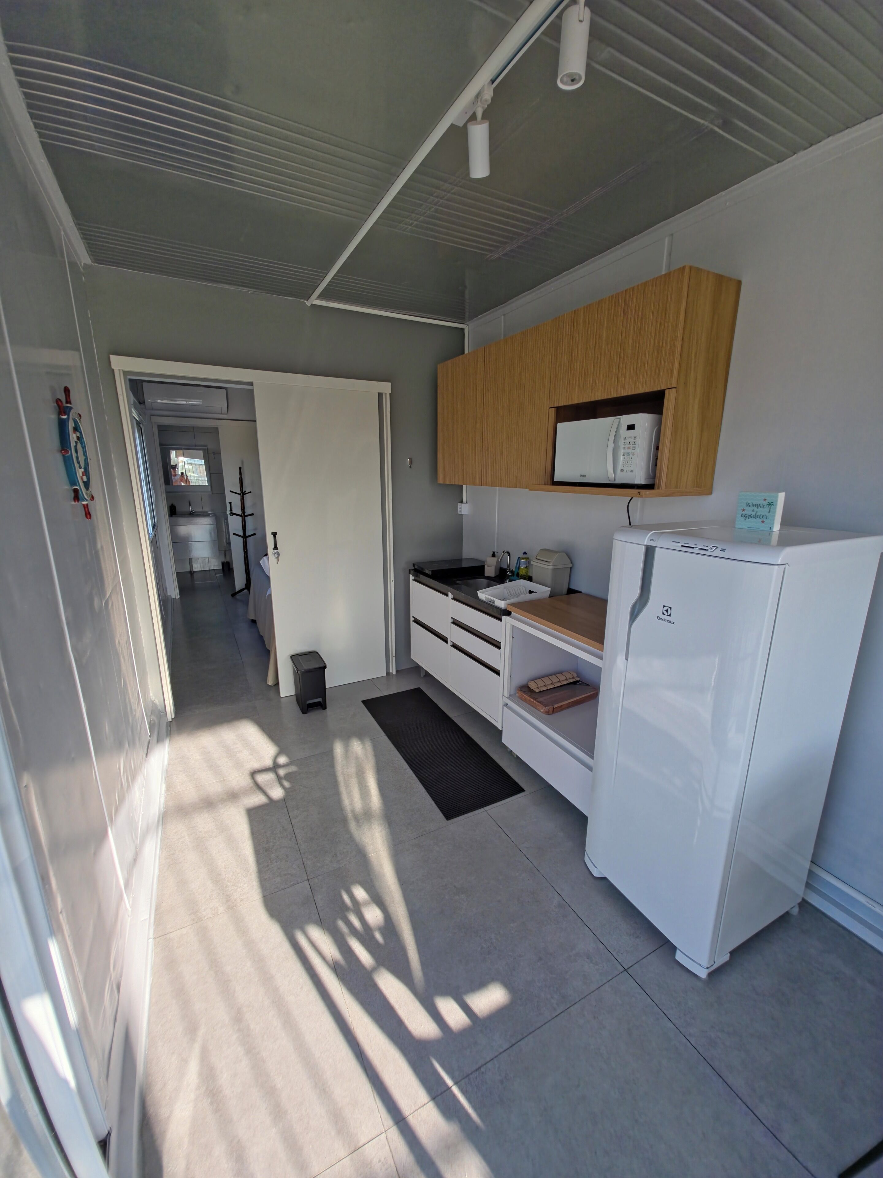 A compact kitchen with a refrigerator, microwave, and wooden cabinets.