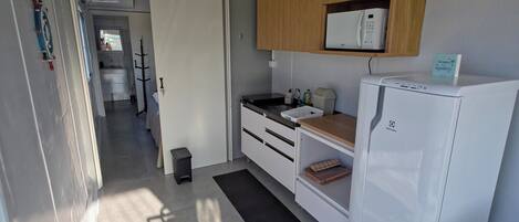 A compact kitchen with a refrigerator, microwave, and wooden cabinets.