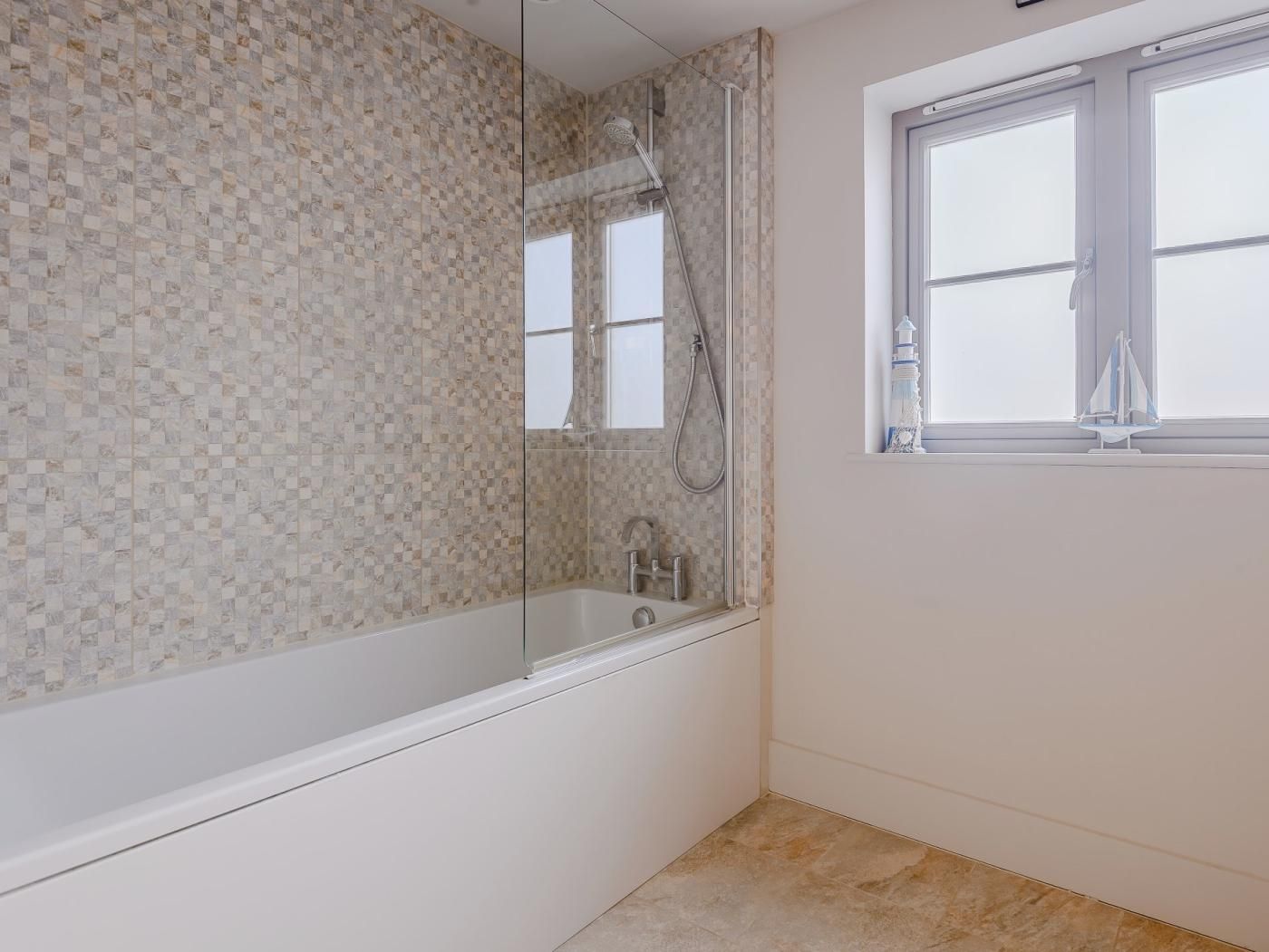 Une salle de bain avec un mur carrelé, une baignoire, une douche et une fenêtre donnant sur un beau paysage.