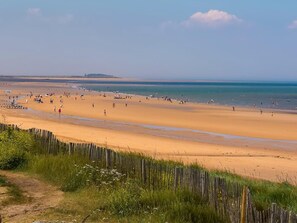 A wide sandy beach with a wooden fence in the foreground. - 3 Bed in Burnham Deepdale (oc-kt045) (Brancaster Staithe)