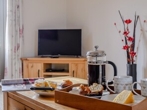 Ein Frühstücksbuffet mit Gebäck, einer Kaffeekanne und einem Fernseher im Hintergrund.