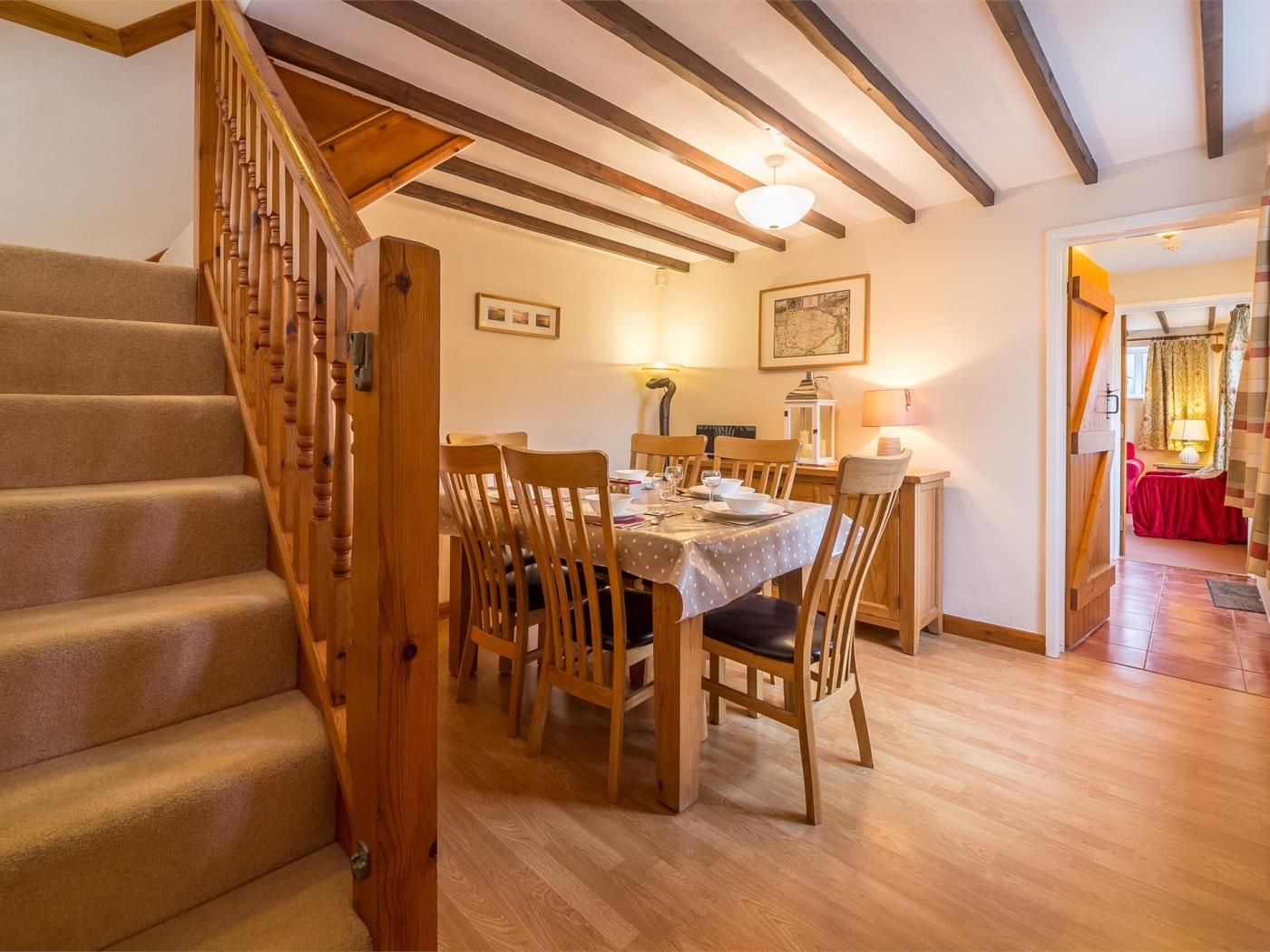 A dining area with a wooden staircase, a table set for four, and a chandelier.