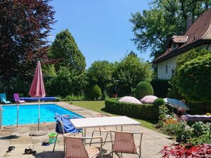 En trädgård med pool, utemöbler och en välskött trädgårdsanläggning.