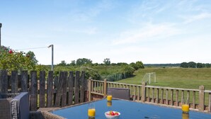 Ein Sitzbereich im Freien mit Tisch, Stühlen und Blick auf ein Fußballfeld.