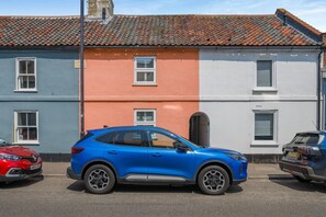 A blue car parked in front of a building with a red and white facade, a red car to the left, and a blue car to the right. - 3 Bed in Wells-next-the-sea (oc-kt050) (Wells-next-the-Sea)