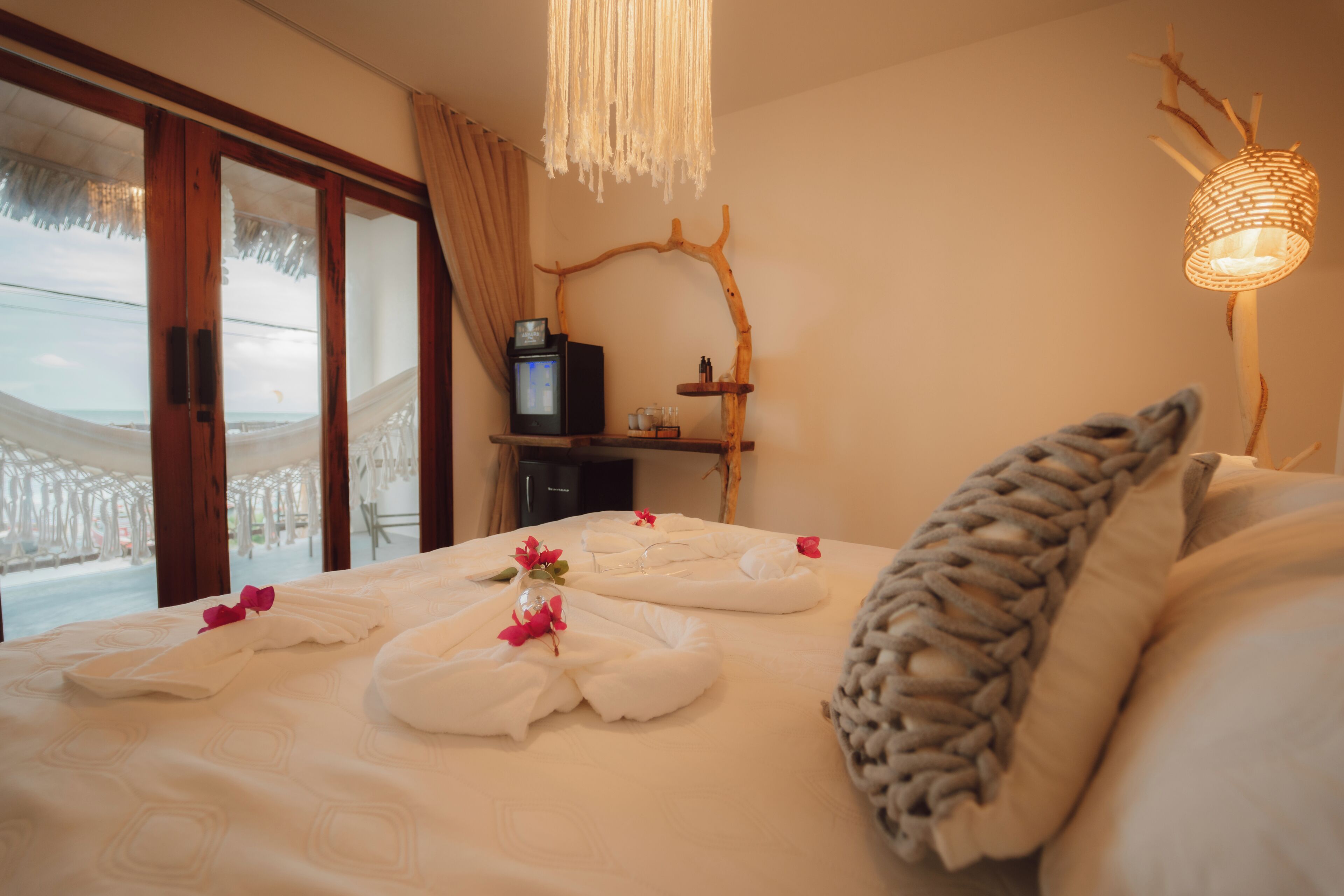 Een hotelkamer met een bed, een televisie, een houten plank en uitzicht op het strand.