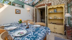 Un comedor con una mesa dispuesta para cuatro personas, un aparador de madera con adornos, y una pared de piedra.