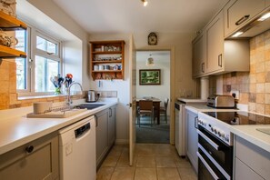 Eine Küche mit Geschirrspüler, Backofen und Essbereich inklusive Tisch und Stühlen.