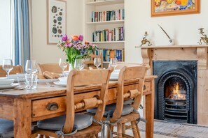 Comedor con mesa de madera, sillas y chimenea.
