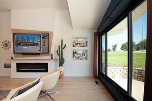 A modern living room with a fireplace, a large TV, and artwork on the wall.