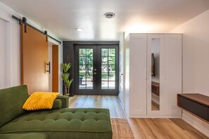 A modern room with a green sofa, a sliding door, a white wardrobe, and a television.