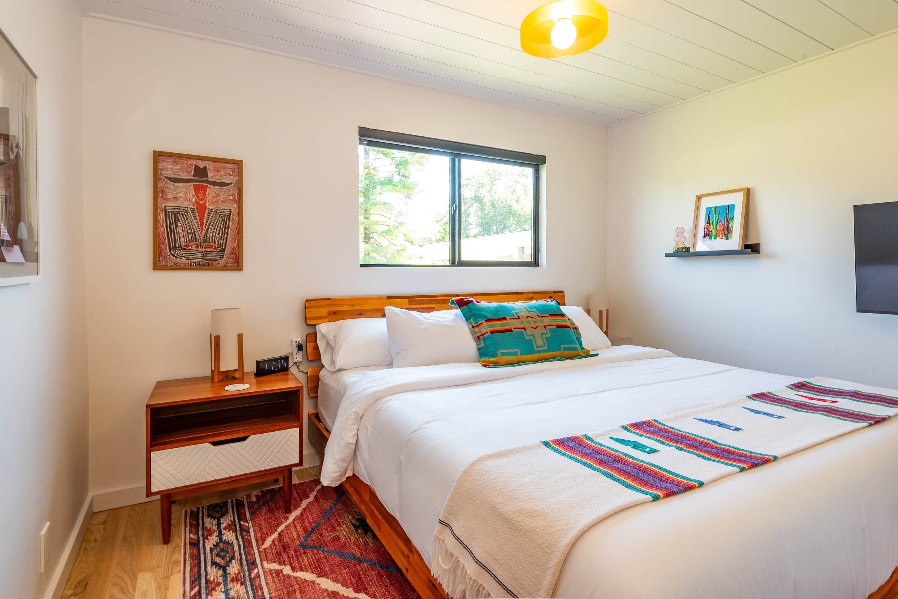 Ein Schlafzimmer mit Bett, Nachttisch, Fenster und Bildern an der Wand.