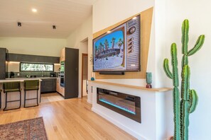 A modern kitchen with a built-in oven, a bar area with stools, and a large cactus plant.