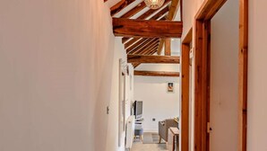 A narrow hallway with wooden beams, a white wall, and a door leading to a room with a desk and chair. - 2 Bed in Thorpe Market (oc-kt107) (Thorpe Market)