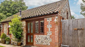 A small brick house with a tiled roof, a wooden door, and a stone wall. - 2 Bed in Thorpe Market (oc-kt107) (Thorpe Market)
