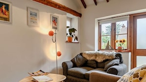 A cozy living room with a sofa, a small table, a floor lamp, and a window with a view of greenery. - 2 Bed in Thorpe Market (oc-kt107) (Thorpe Market)