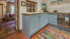 Een keuken met blauwe kastjes, een houten aanrecht, een fornuis en een kleurrijk vloerkleed.