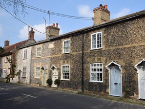 A row of stone houses with multiple windows and doors, a clear sky, and a paved street. - 2 Bed in North Creake (oc-kt003) (North Creake)