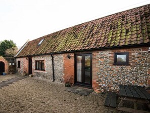 Ein rustikales Gebäude mit Ziegeldach, Steinmauern, einer Holztür und einem kleinen Fenster.