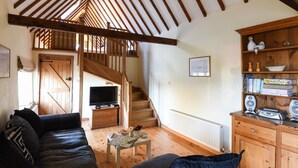 Un salon chaleureux avec un escalier en bois, un téléviseur et une bibliothèque.
