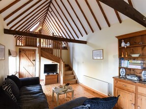 Ein gemütliches Wohnzimmer mit einer Holztreppe, einem Fernseher und einem Bücherregal.