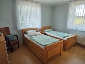 Ein Zimmer mit zwei Holzbetten, einem Sessel und einer Heizung.