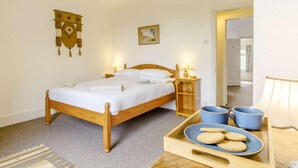 A bedroom with a wooden bed, bedside lamps, a tray with cookies, and a mirror. - 3 Bed in Thornham (oc-kt022) (Thornham)