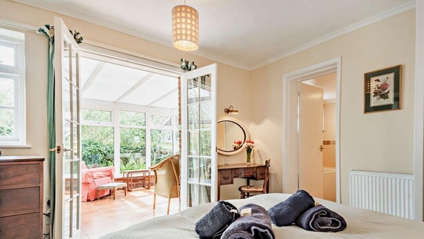 Ein Schlafzimmer mit Bett, Kommode, Schreibtisch, Stuhl, Spiegel und Fenster.