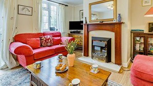 A living room with a red sofa, a fireplace, a television, and a bookshelf. - 2 Bed in Trunch (oc-kt035) (Trunch)