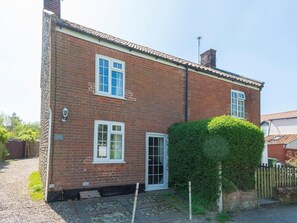 A two-story brick house with white-framed windows, a visible chimney, and a small garden area with a hedge. - 2 Bed in Trunch (oc-kt035) (Trunch)