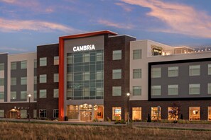 Un hotel de varios pisos con un llamativo letrero 'CAMBRIA', ventanas amplias y un techo plano.