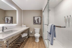 Un baño moderno con ducha de vidrio, inodoro y lavamanos con toallero.