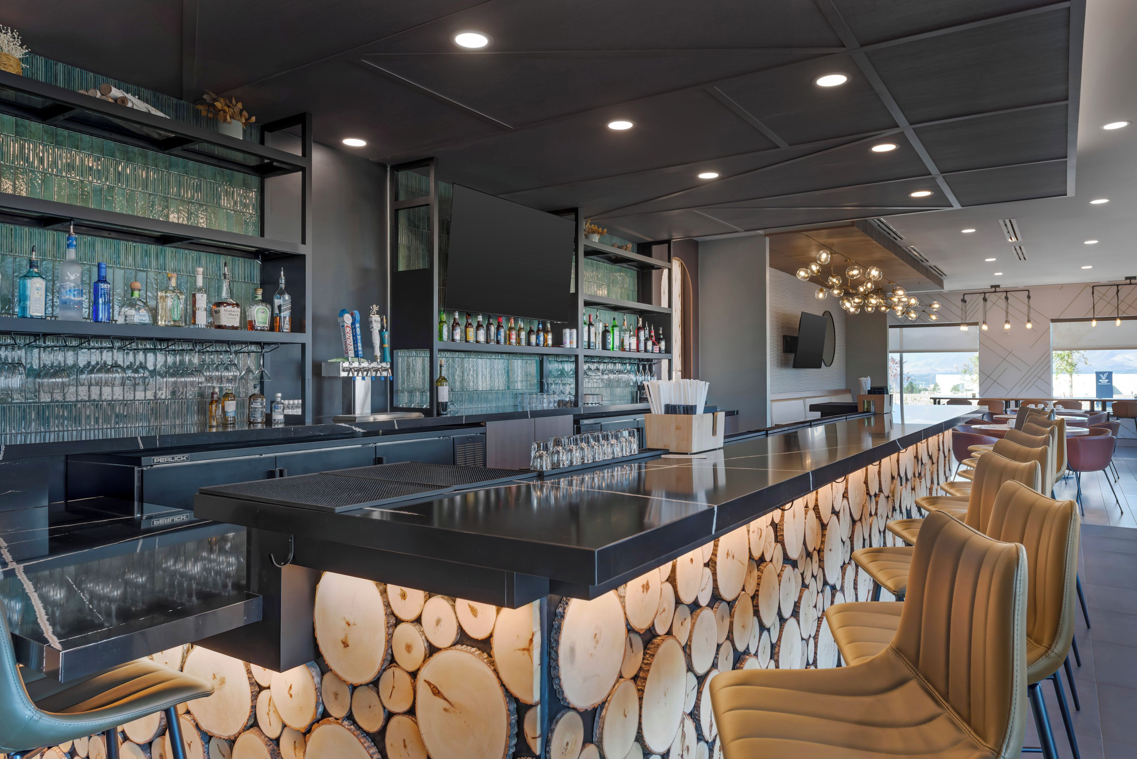 A bar area with a long counter, multiple shelves of bottles, and bar stools.