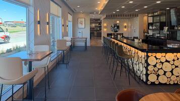 Un espace bar moderne, doté d’un comptoir, de sièges et offrant une vue sur l’extérieur.