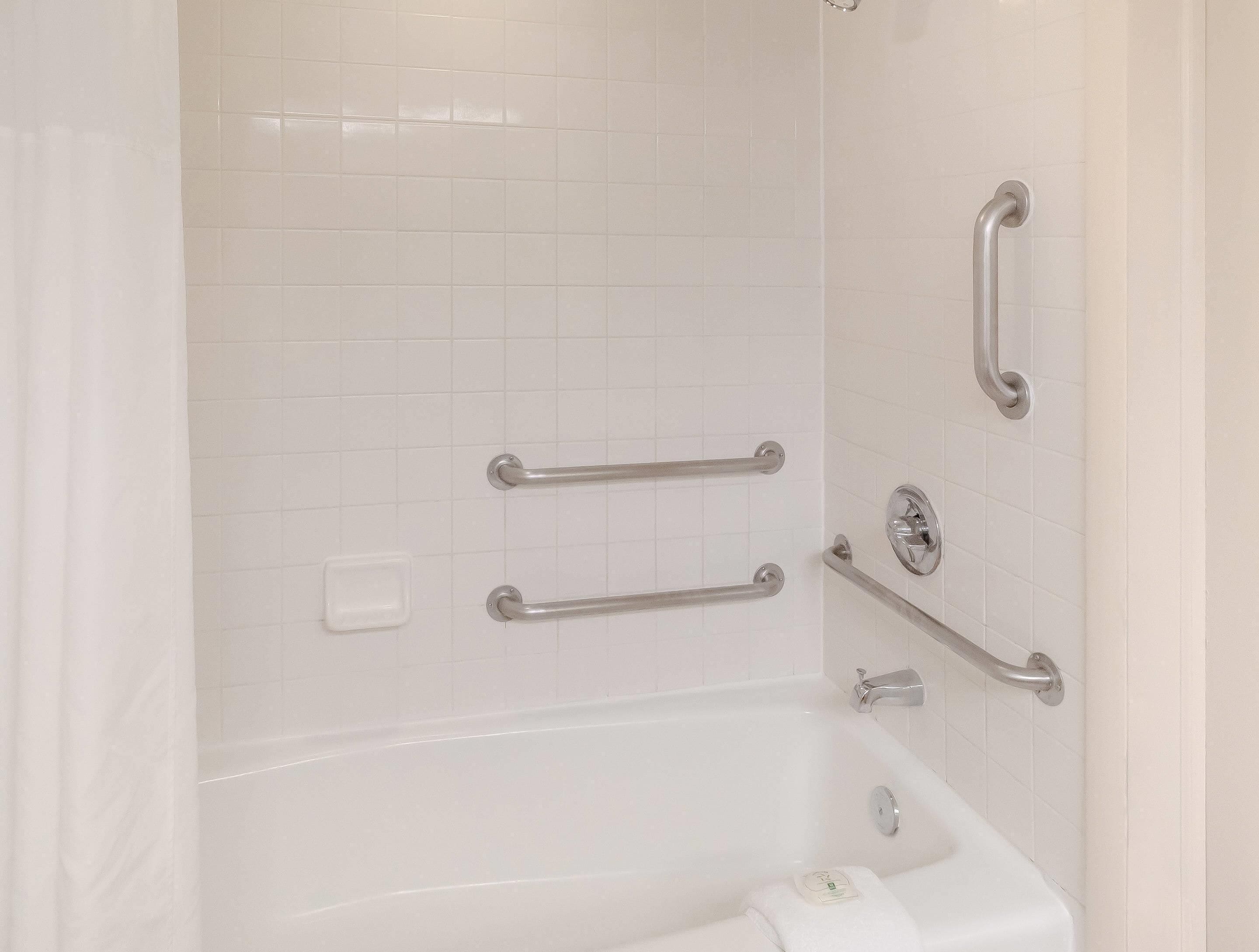 Ein Badezimmer mit einer Badewanne, Haltegriffen und einer Seifenschale.