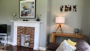 Ein Wohnzimmer mit Kamin, Fernseher, Sofa und Lampe.