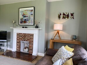 Ein Wohnzimmer mit Kamin, Fernseher, Sofa und Lampe.