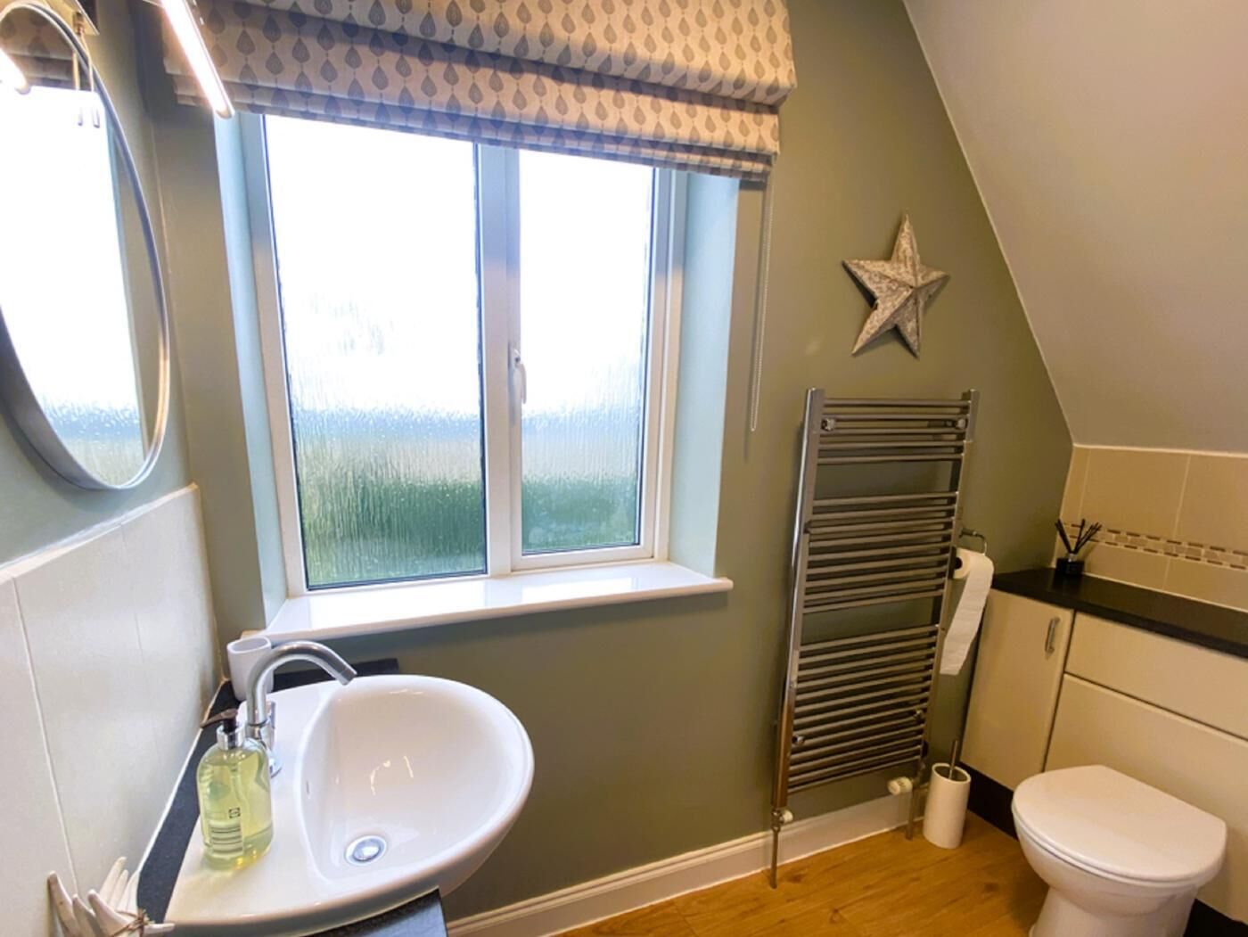 Une salle de bain avec une fenêtre, un lavabo, un porte-serviettes et des toilettes.