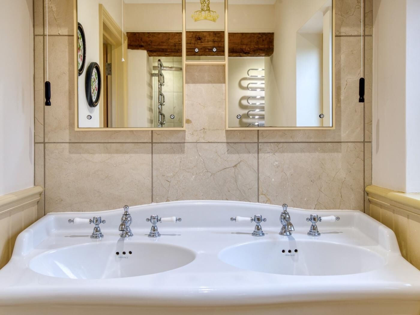 A bathroom with a large white sink, two faucets, and a mirror above.