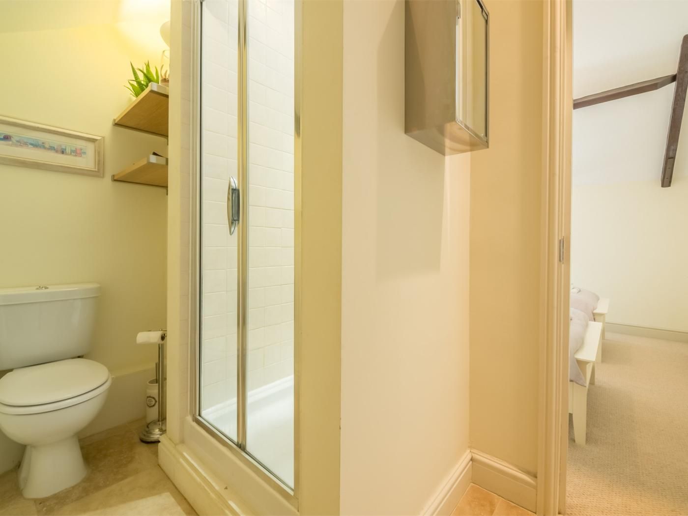 Une salle de bain comprenant des toilettes, une douche avec une porte en verre et un lavabo.
